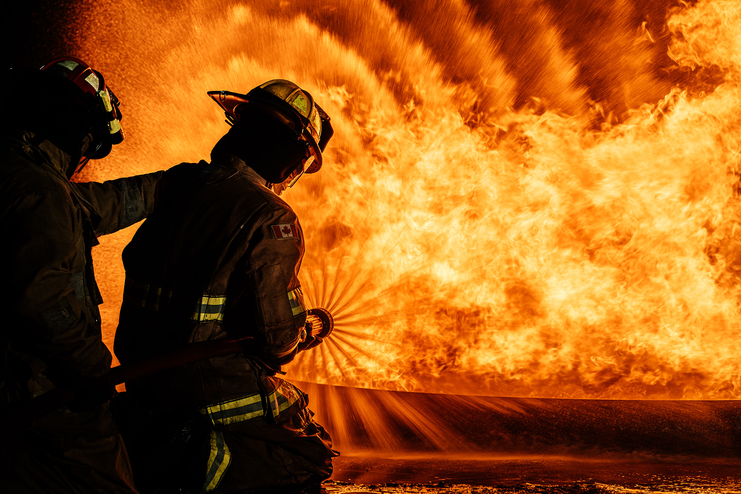 Firefighters spraying water on burning car